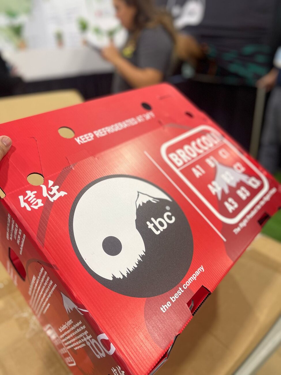 Close-up of a TBC carton showing the yin-yang mark, 信任 and Keep Refrigerated at 34°F